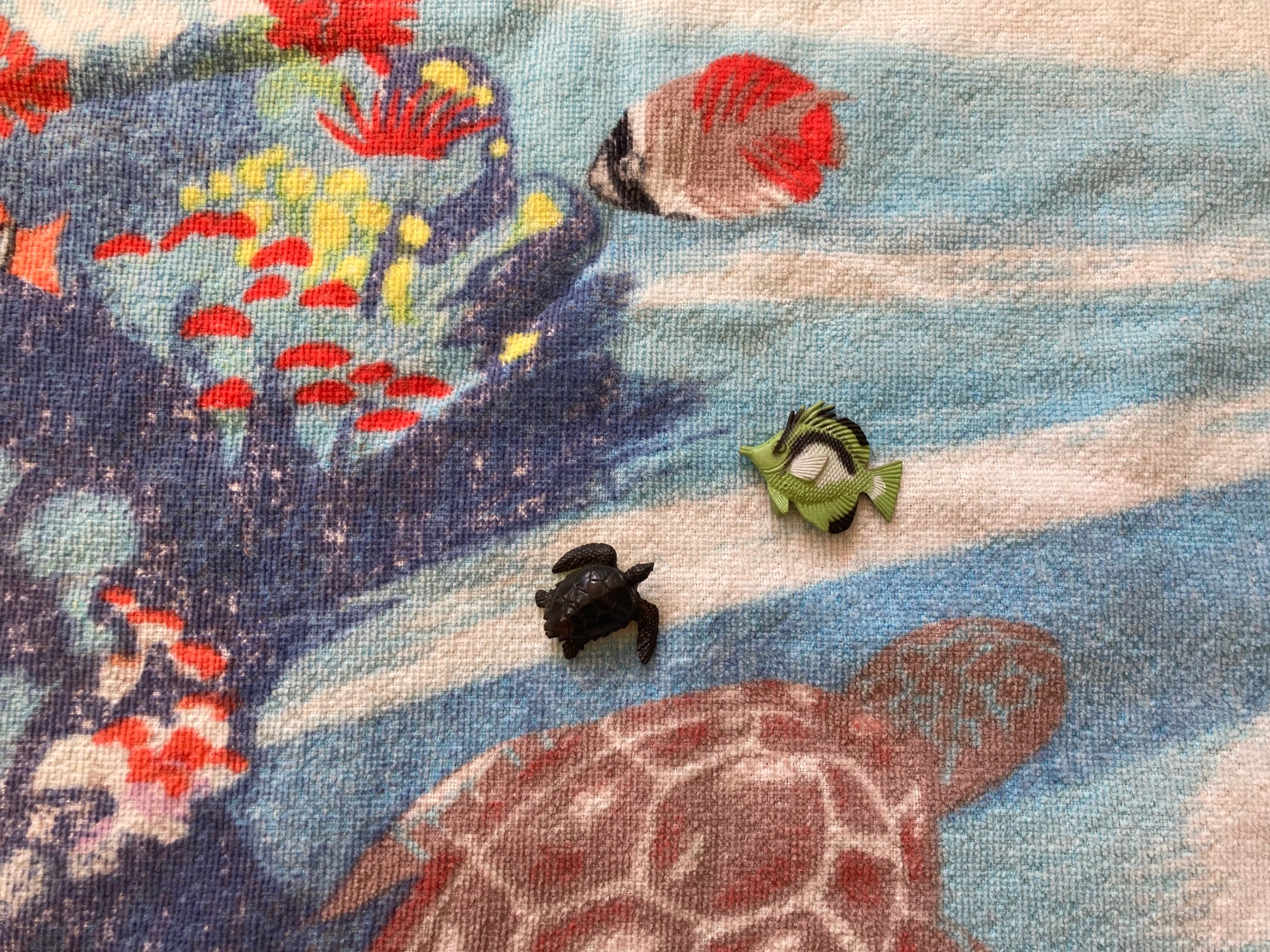 A beach towel with a brown turtle with blue coral watercolor print