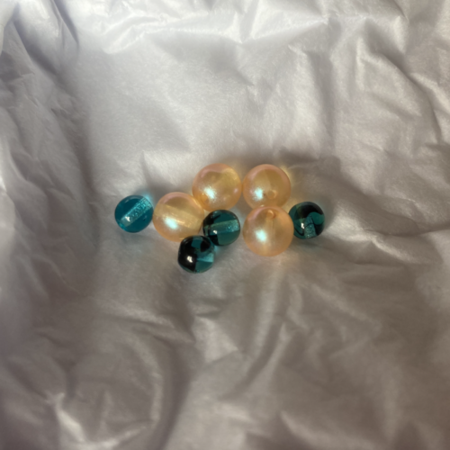 A photo of four peach-colored beads and four teal-colored beads