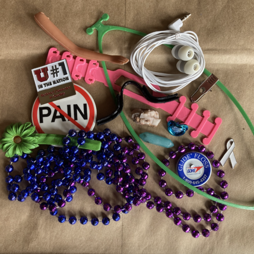 A photo of miscellaneous drop box submissions including pins, plastic beads, and the arm of a doll