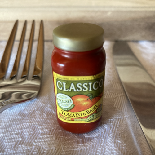 A photo of a fork and a miniature bottle of spaghetti sauce