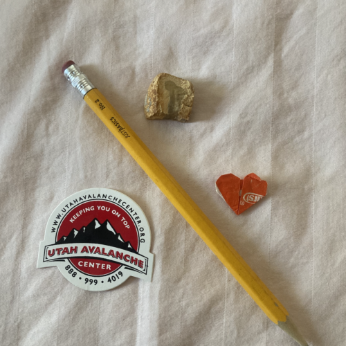 A photo of a sticker, a pencil, a geode, and a heart wrapper